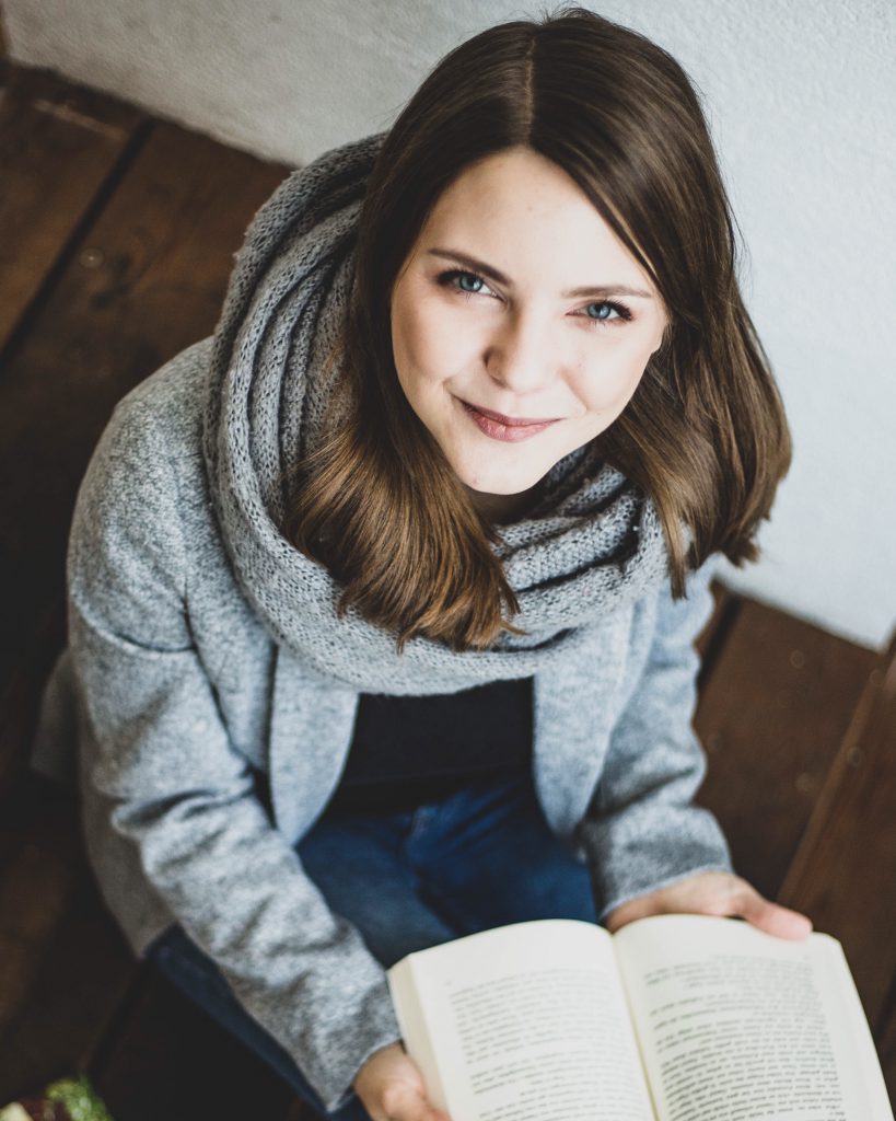 Frau sitzt auf einer Treppe und hält ein Buch in der Hand