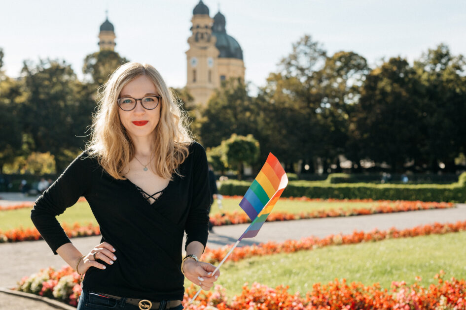 Foto: Frau mit Regenbogenfahne in der Hand.